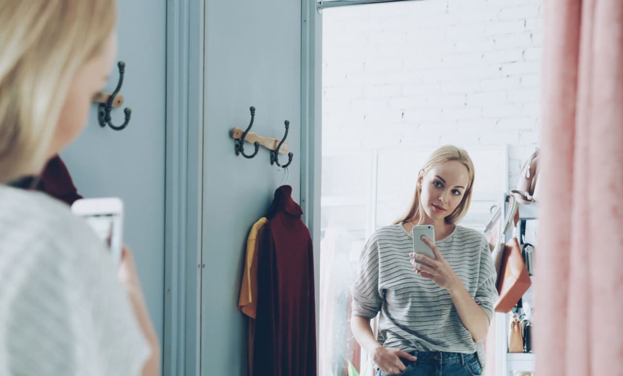 Donna in camerino che si guarda allo specchio, tema accettare il proprio corpo e immagine corporea